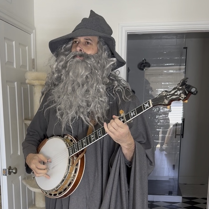 Mike in a wizard costume, playing the banjo